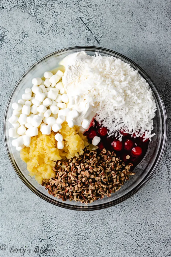 Top down view of pie filling, pineapples, pecans, marshmallows, and coconut in a bowl.