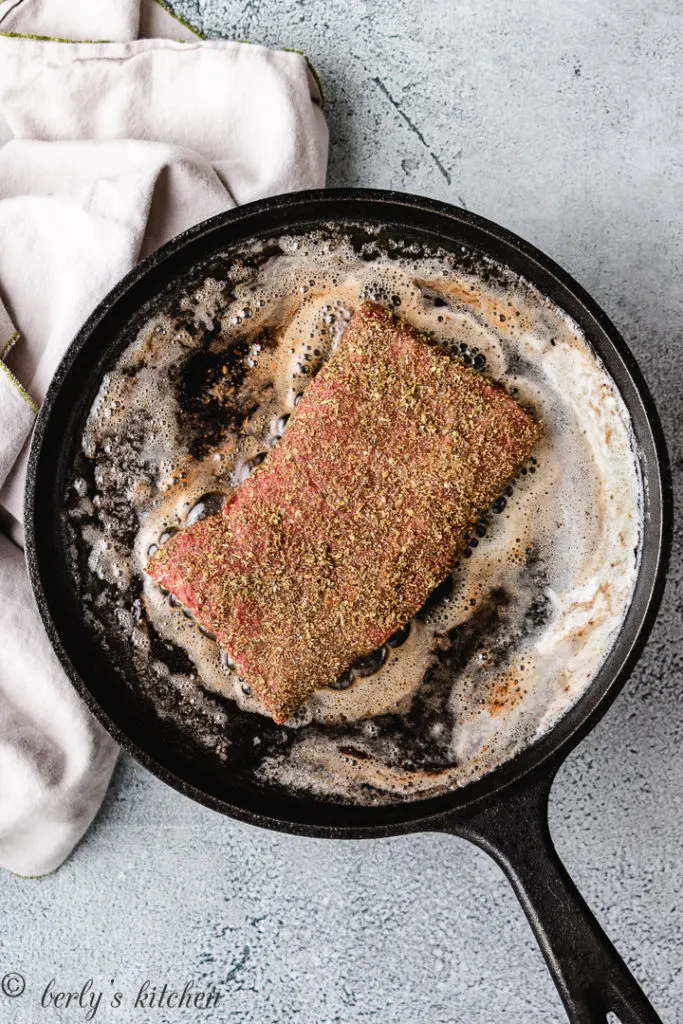 Flat iron steak cooking in butter.