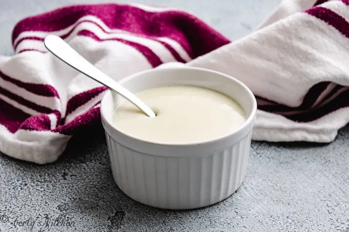 Sweetened condensed milk with a metal spoon and purple towel.