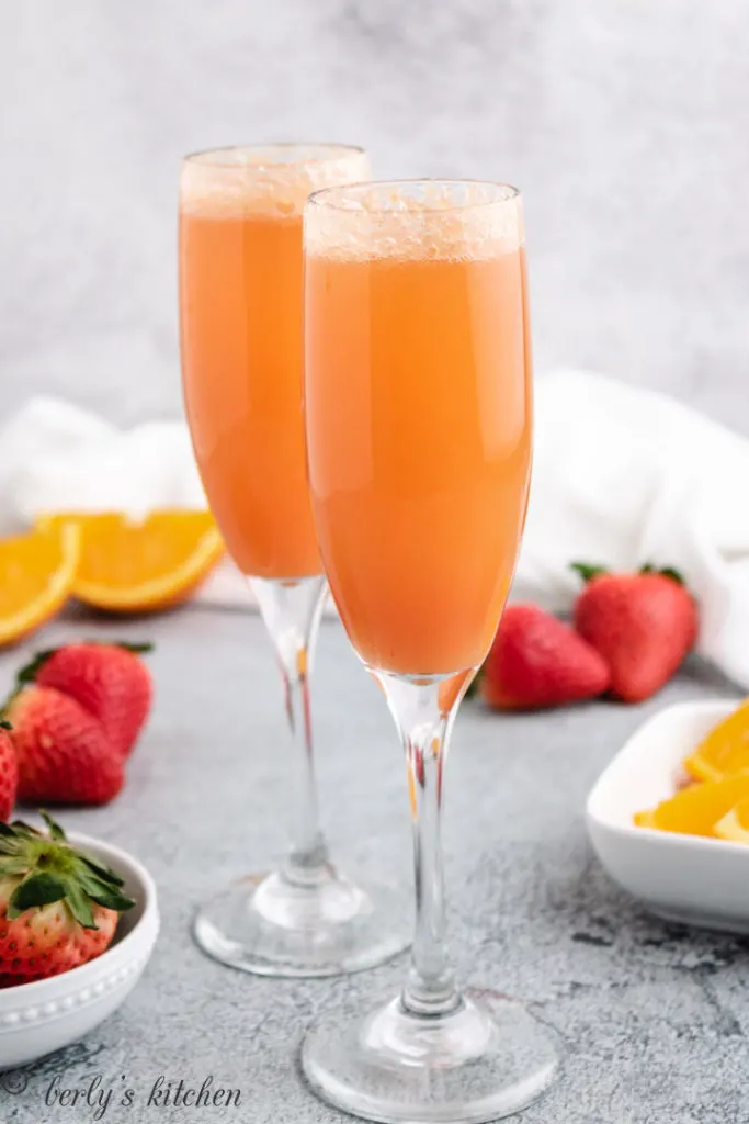 Two champagne glasses filled with strawberry mimosas.