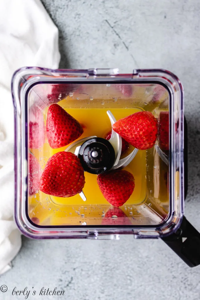 Strawberries and orange juice in a blender.