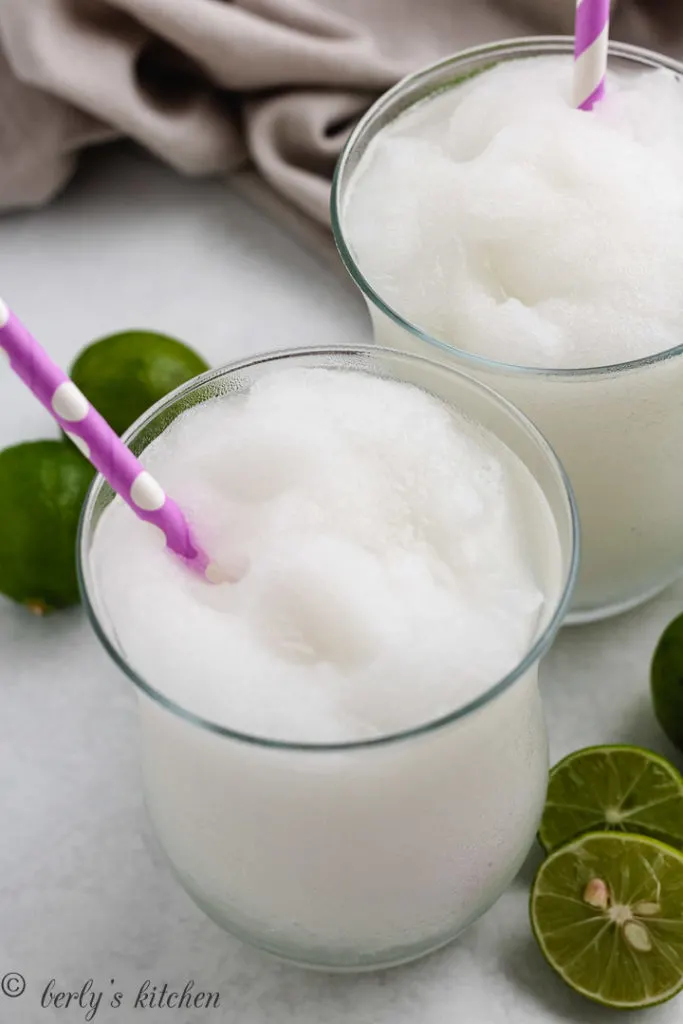 Top down view of a frozen drink next to key limes.