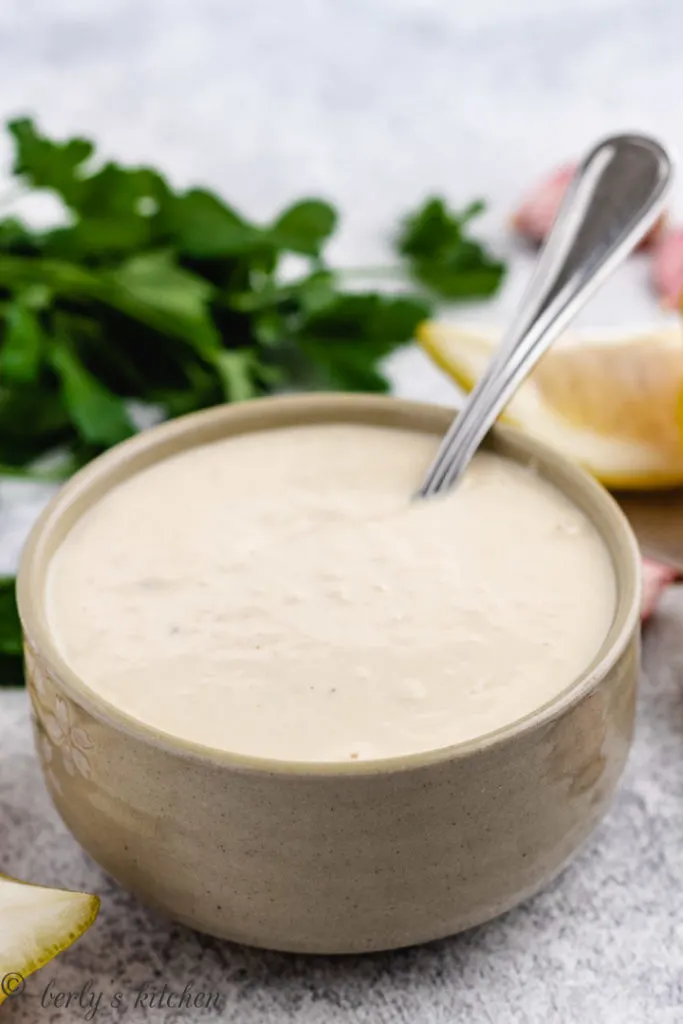 Bowl of caesar dressing with a metal spoon.