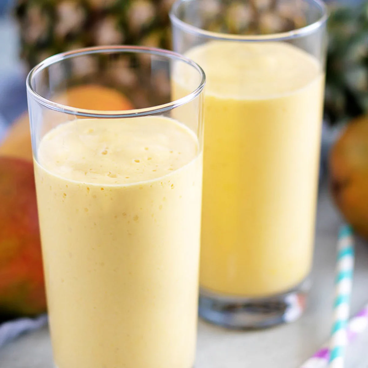 Pineapple smoothie with mango with colorful straws.