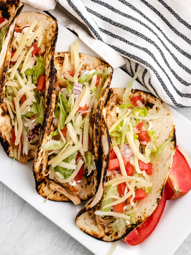 Tacos lined up on a white platter.