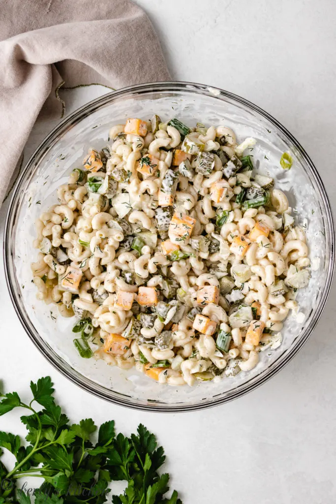 Top down view of pickle pasta salad in a glass bowl.