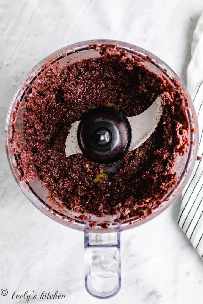 Top down view of olive tapenade in a food processor.