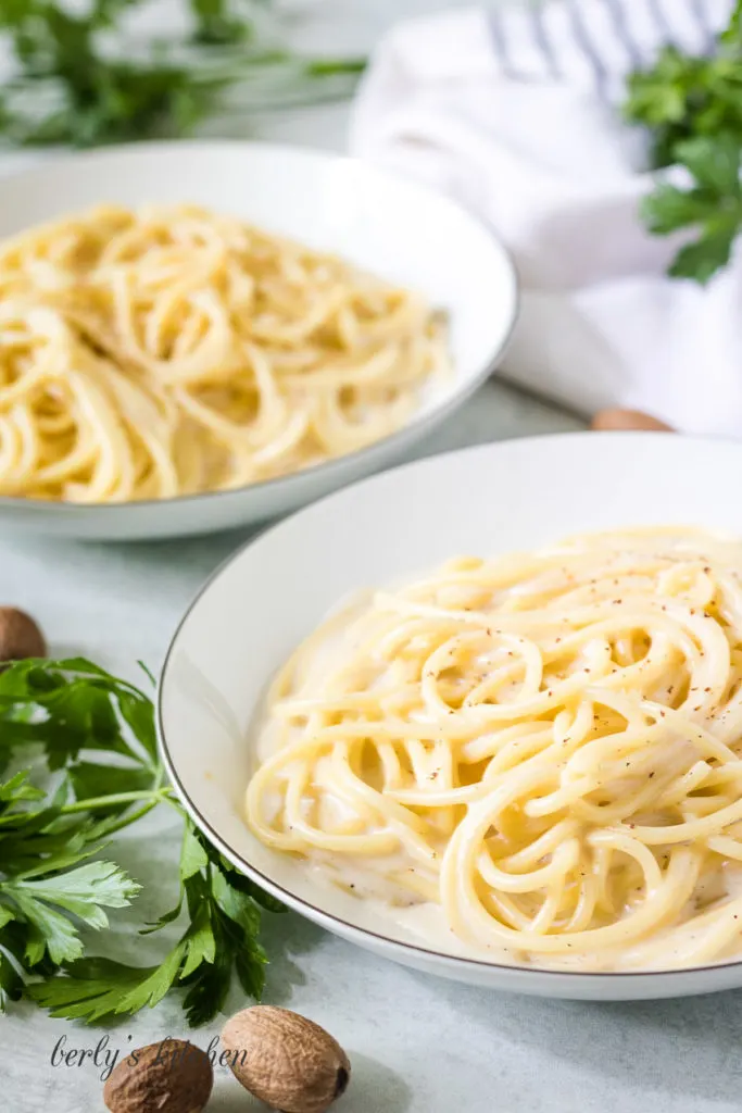 Two bowls of pasta tossed in white sauce.