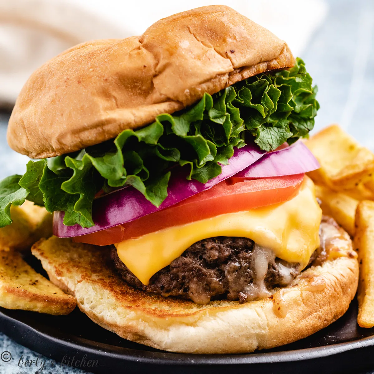 Stuffed burger on a black plate.