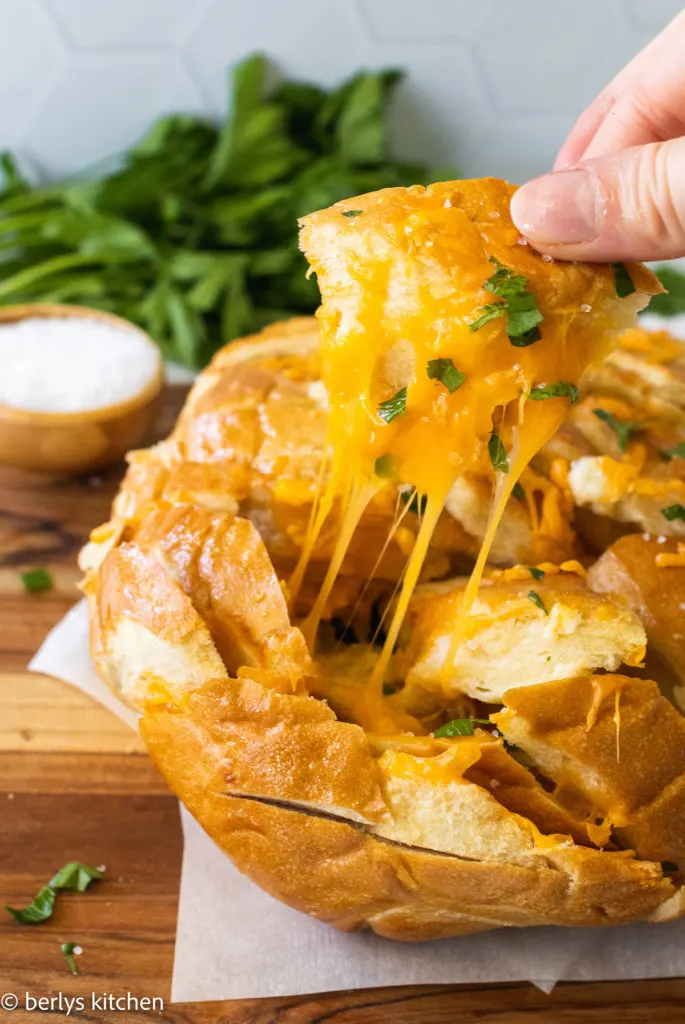 Piece of garlic pull apart bread being pulled from a loaf.