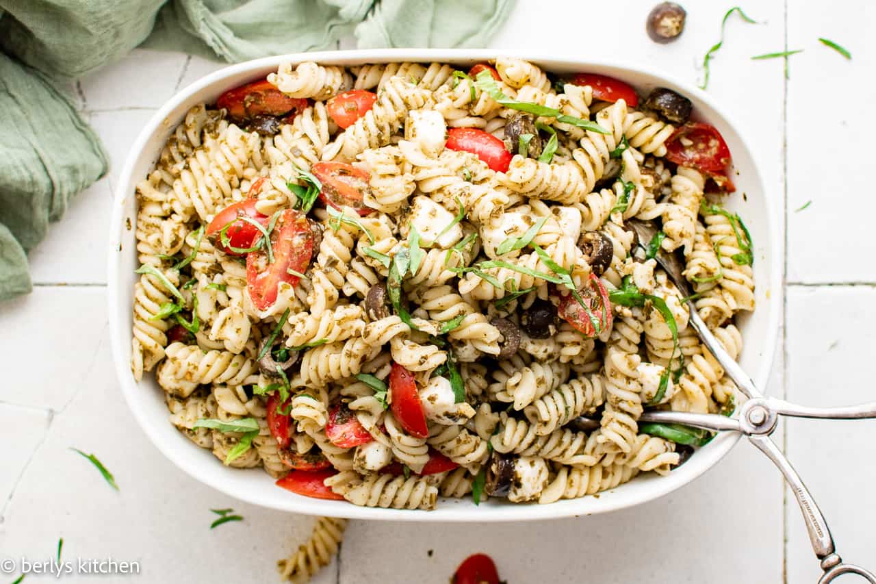 Top down view of pasta salad in a large serving dish with serving spoon.