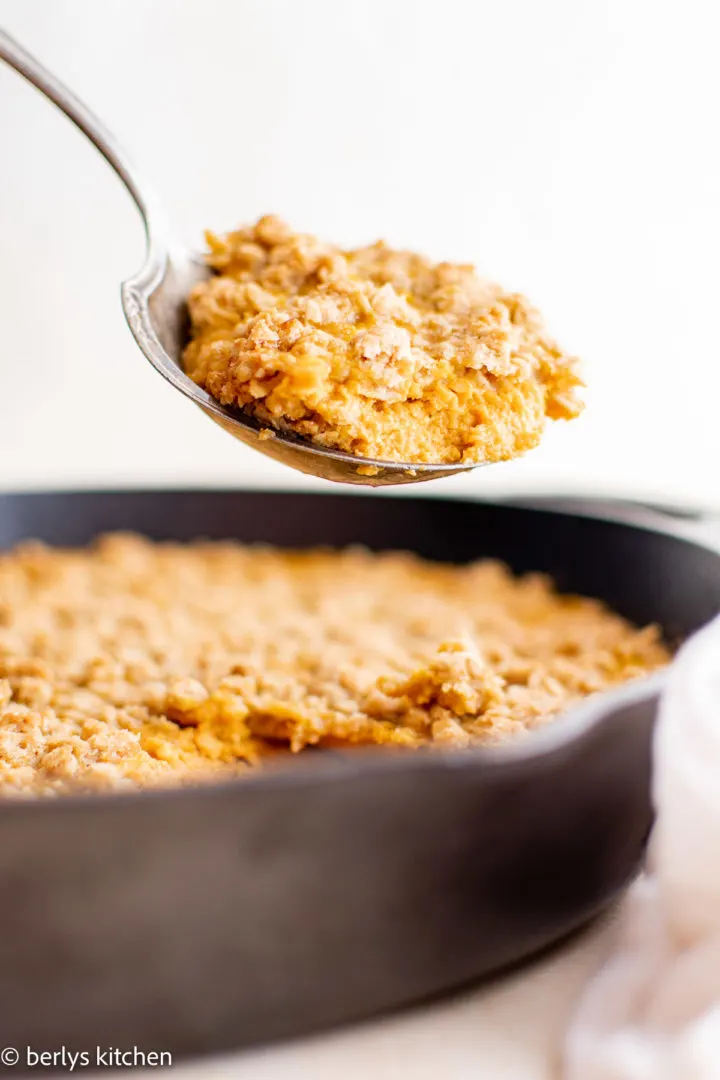 Spoon scooping pumpkin crisp out of a pan.