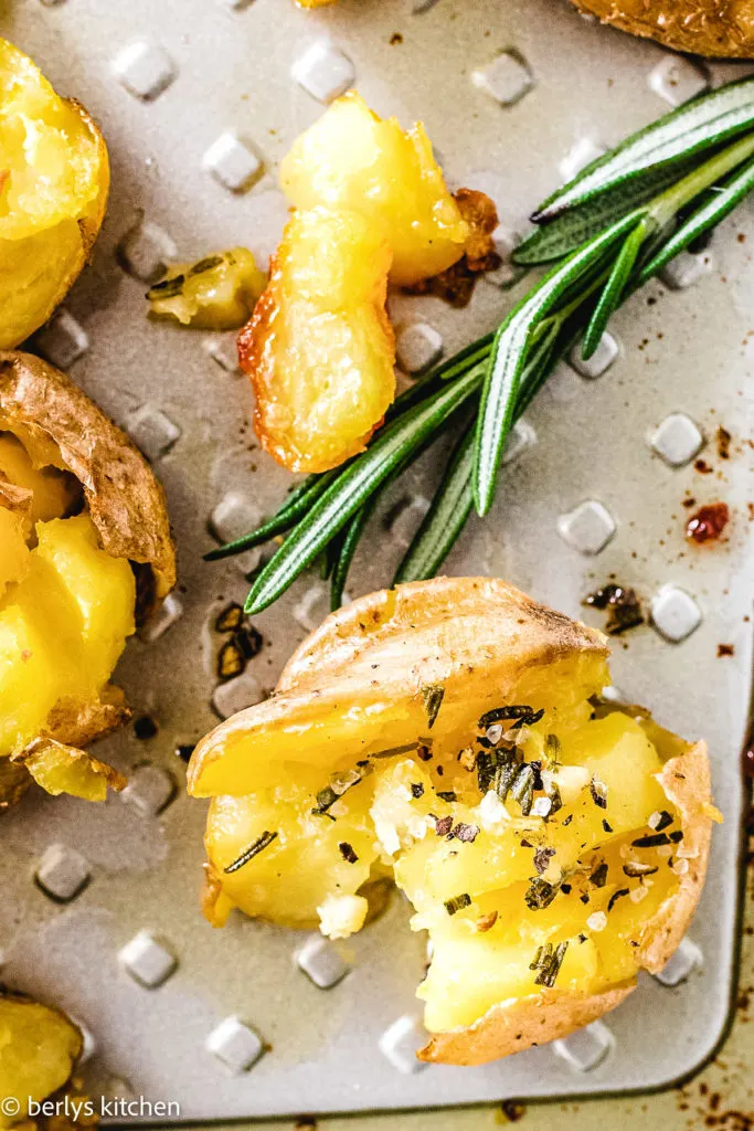 Close up a a baby gold potato with rosemary butter.