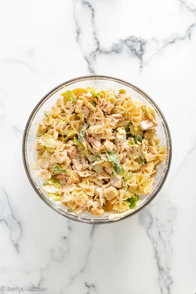 Chicken caesar pasta salad in a glass bowl.