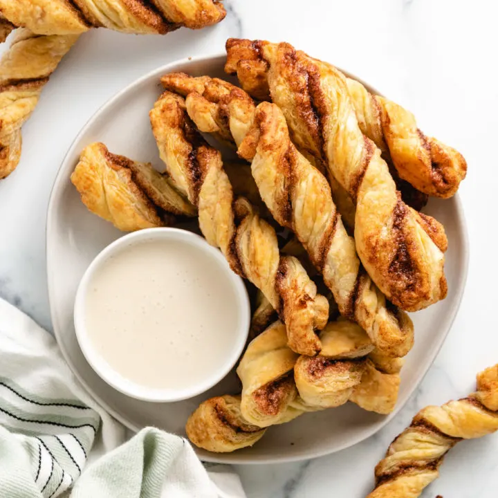 Top down view of cinnamon sticks on a plate with frosting.