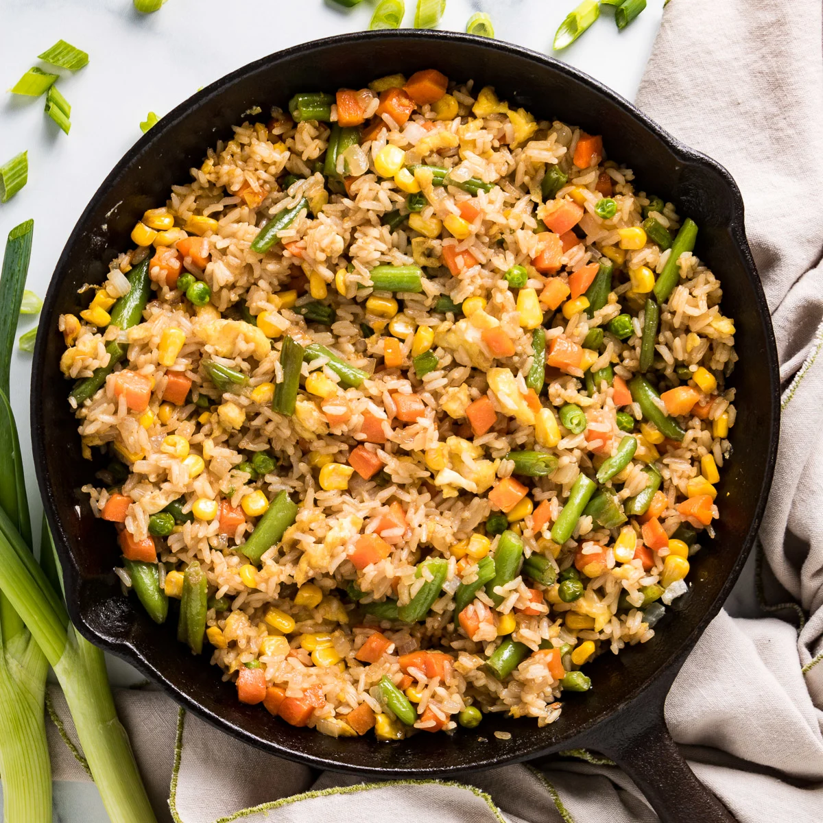 Top down view of rice with vegetables in a black pan.