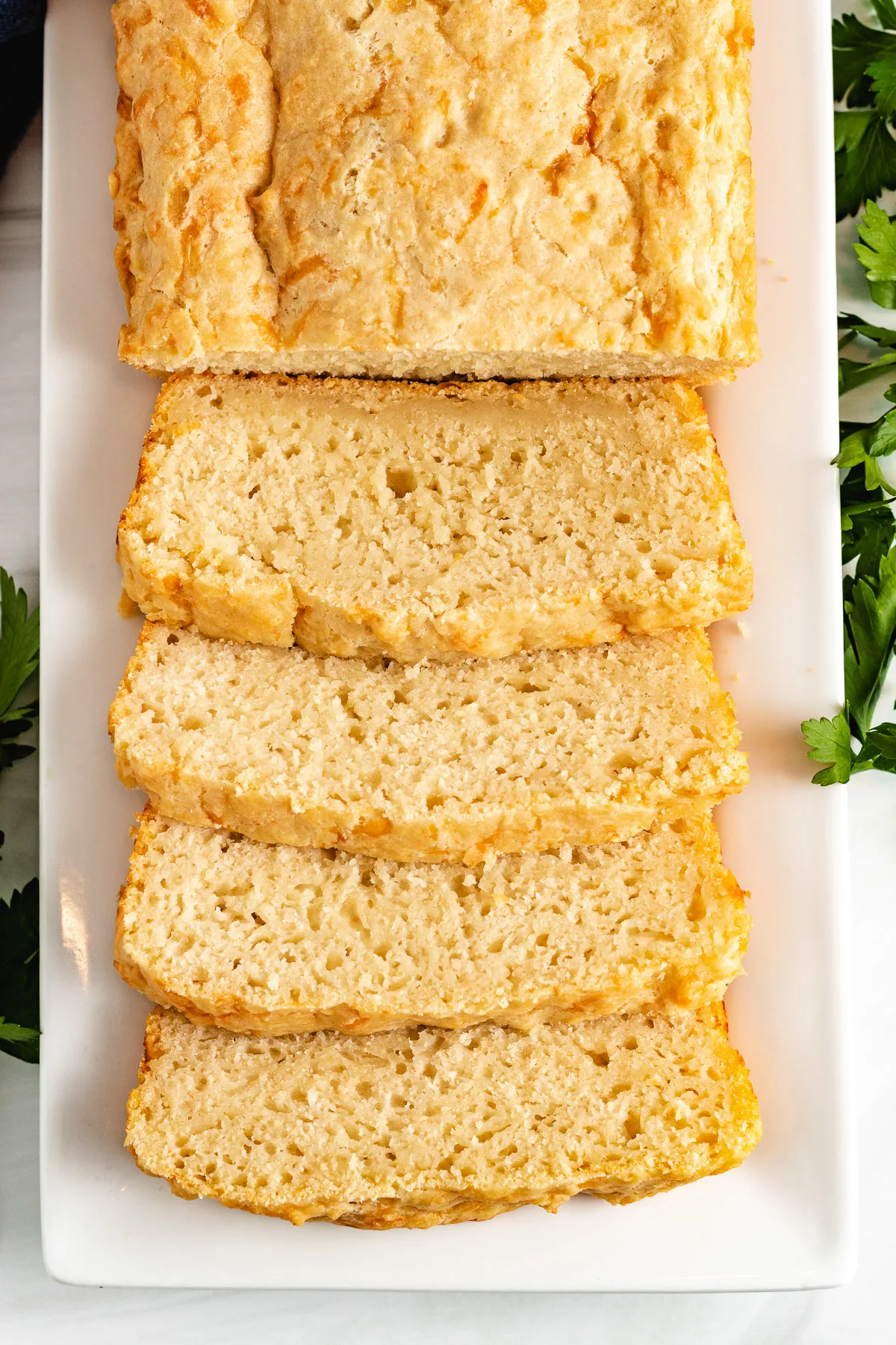 Top down view of cheesy beer bread on a serving platter.