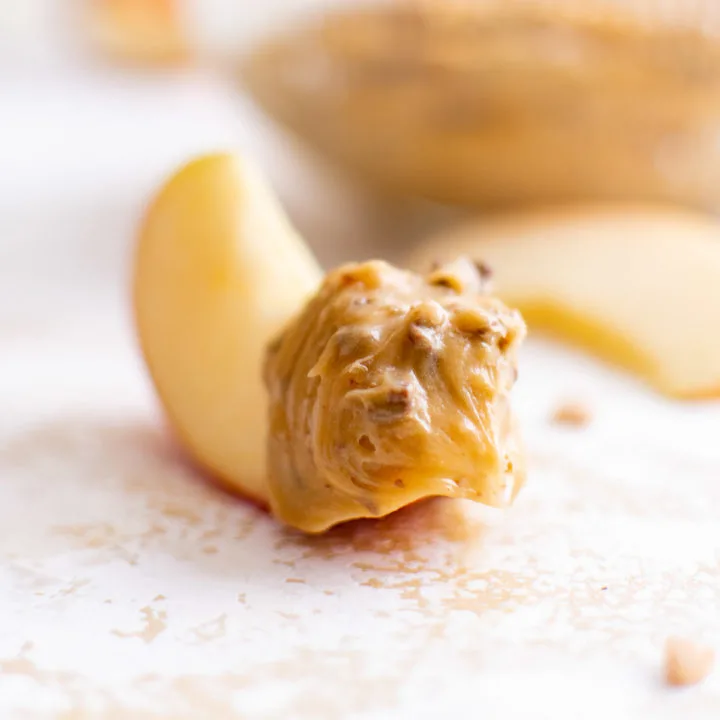 Apple slice dipped in caramel dip.