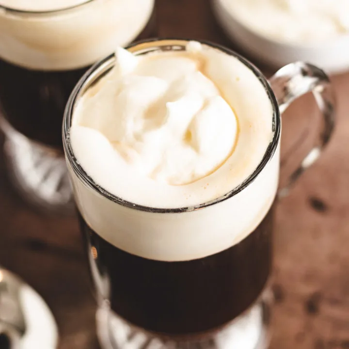 Top down view of dark coffee topped with whipped cream.