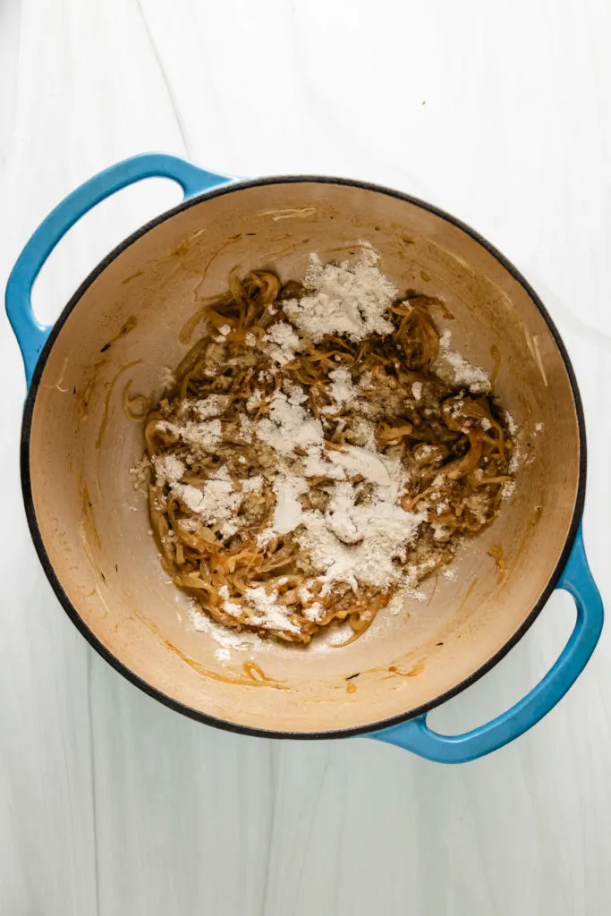 Top down view of flour sprinkled over caramelized onions.