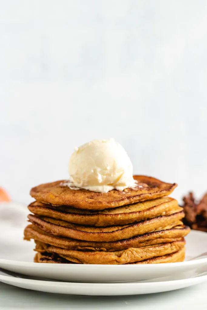 Tall stack of pumpkin pancakes with a scoop of butter.  