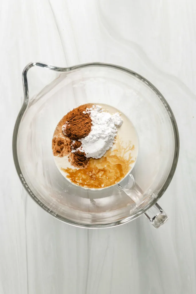 Top down view of ingredients for spiced whipped cream in a mixing bowl.