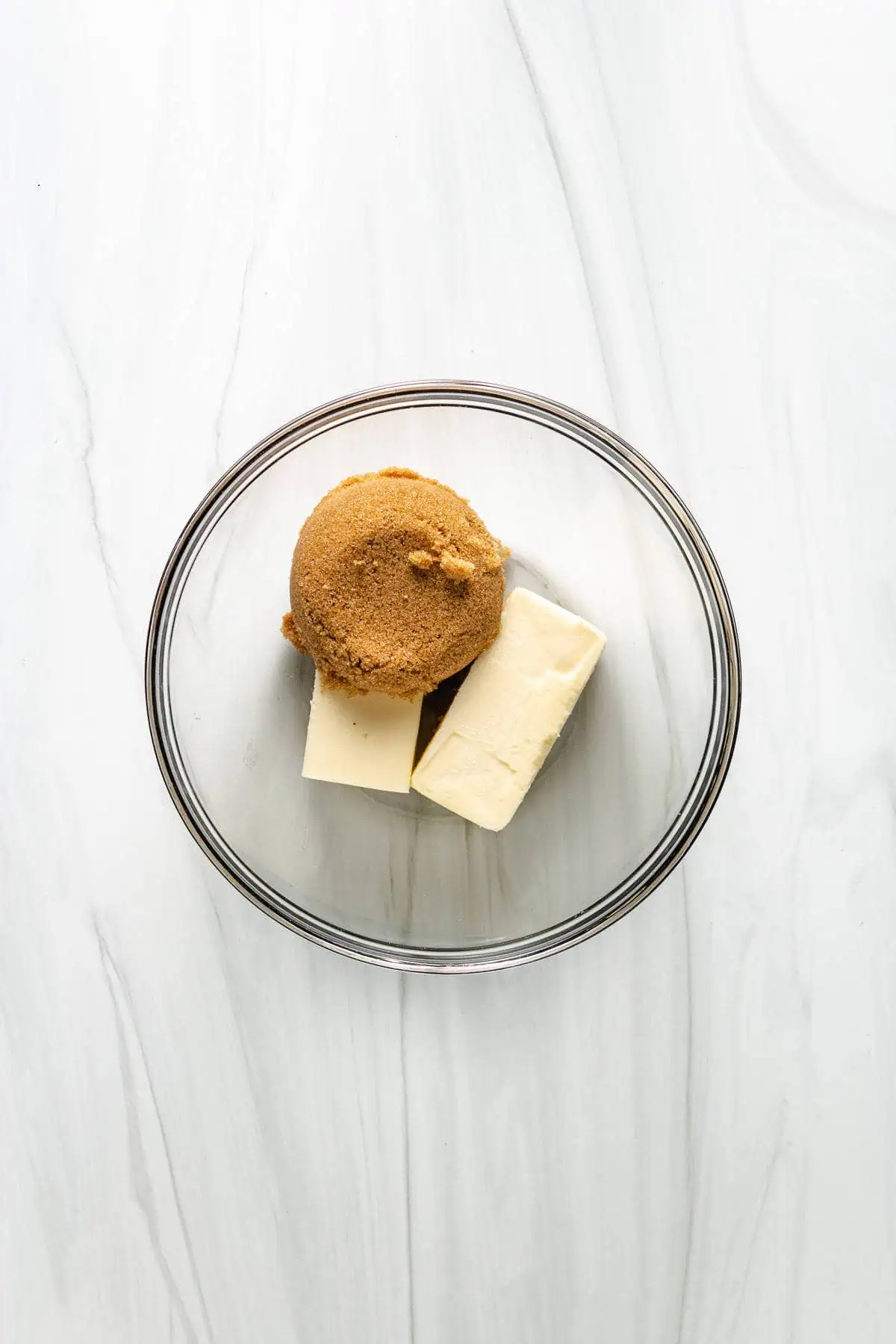 Top down view of unmelted butter and sugar in a bowl.