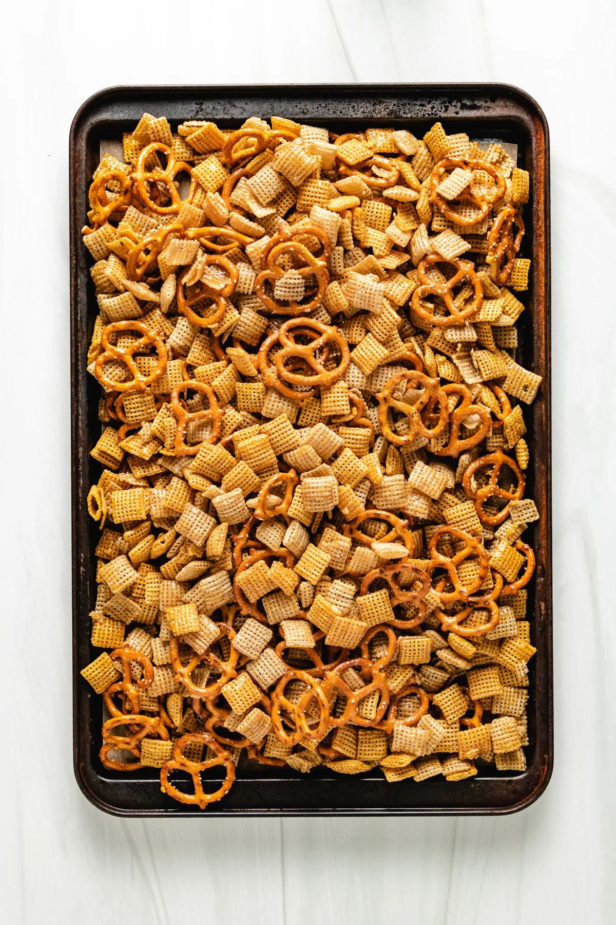 Top down view of baked snack mix on a sheet pan.