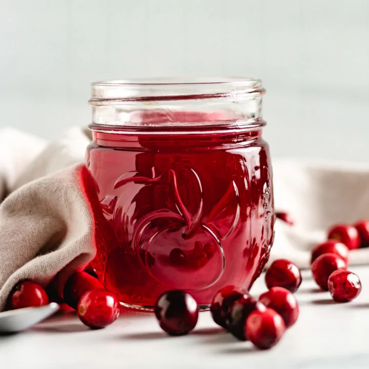 Cranberry simple syrup in a jar with fresh cranberries.