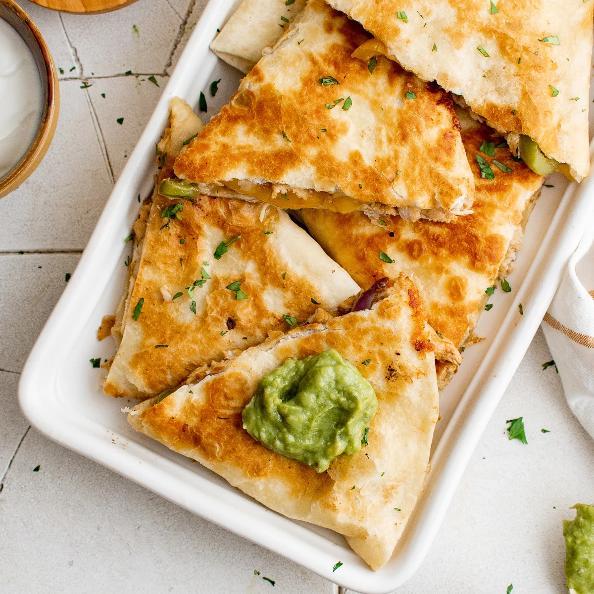 Several pieces of fajita quesadilla on a white platter.