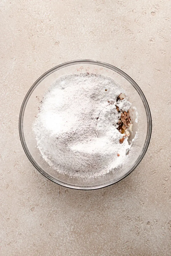 Powdered sugar mixed with cocoa in a bowl with vanilla and milk.