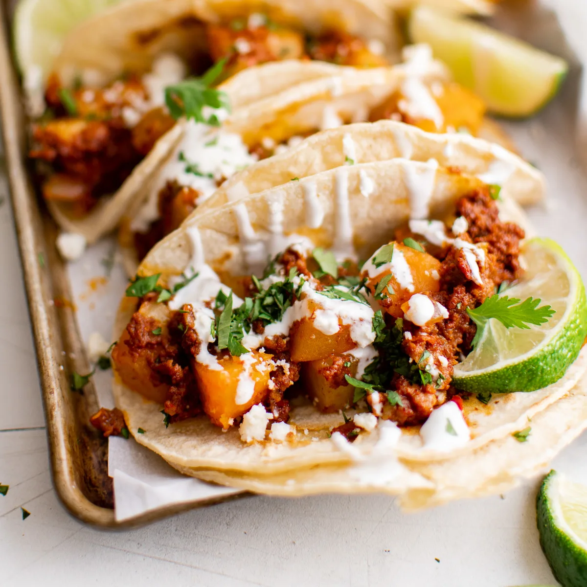 Side view of chorizo tacos with crema and avocado.