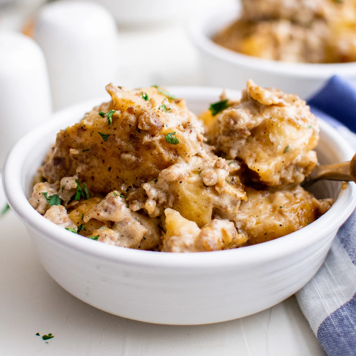 White dish with biscuits and gravy casserole and a spoon.