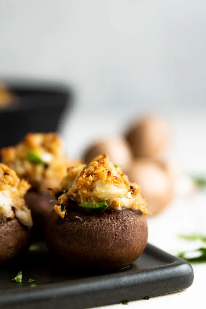 Crab stuffed mushrooms on a black platter.