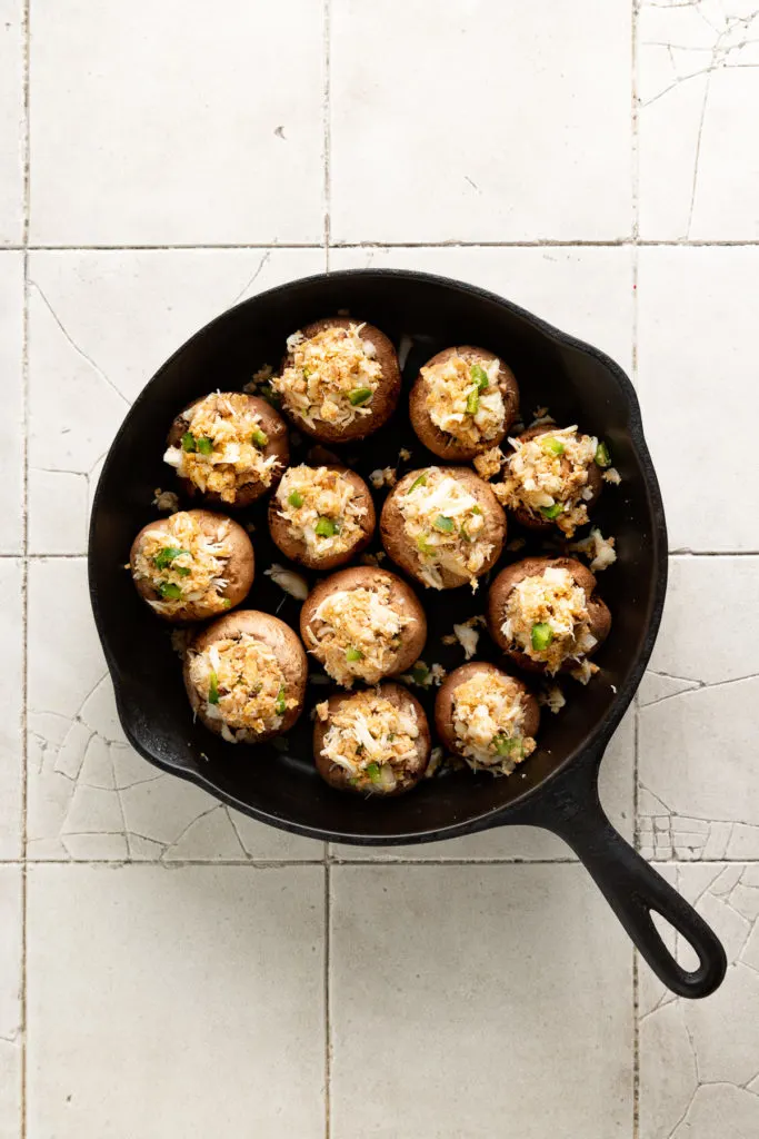 Unbaked stuffed mushrooms in cast iron.