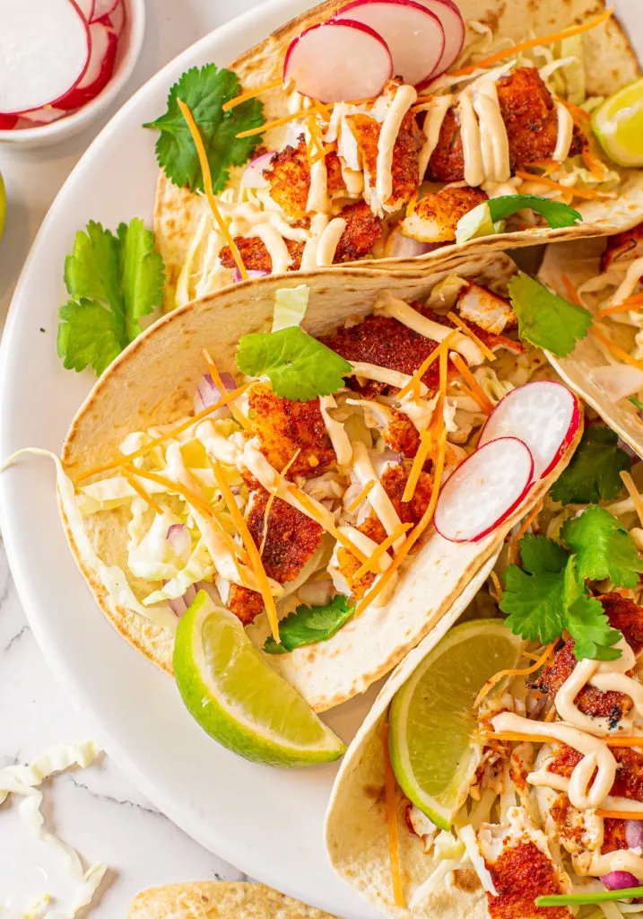 Limes and radish slices with fish tacos.