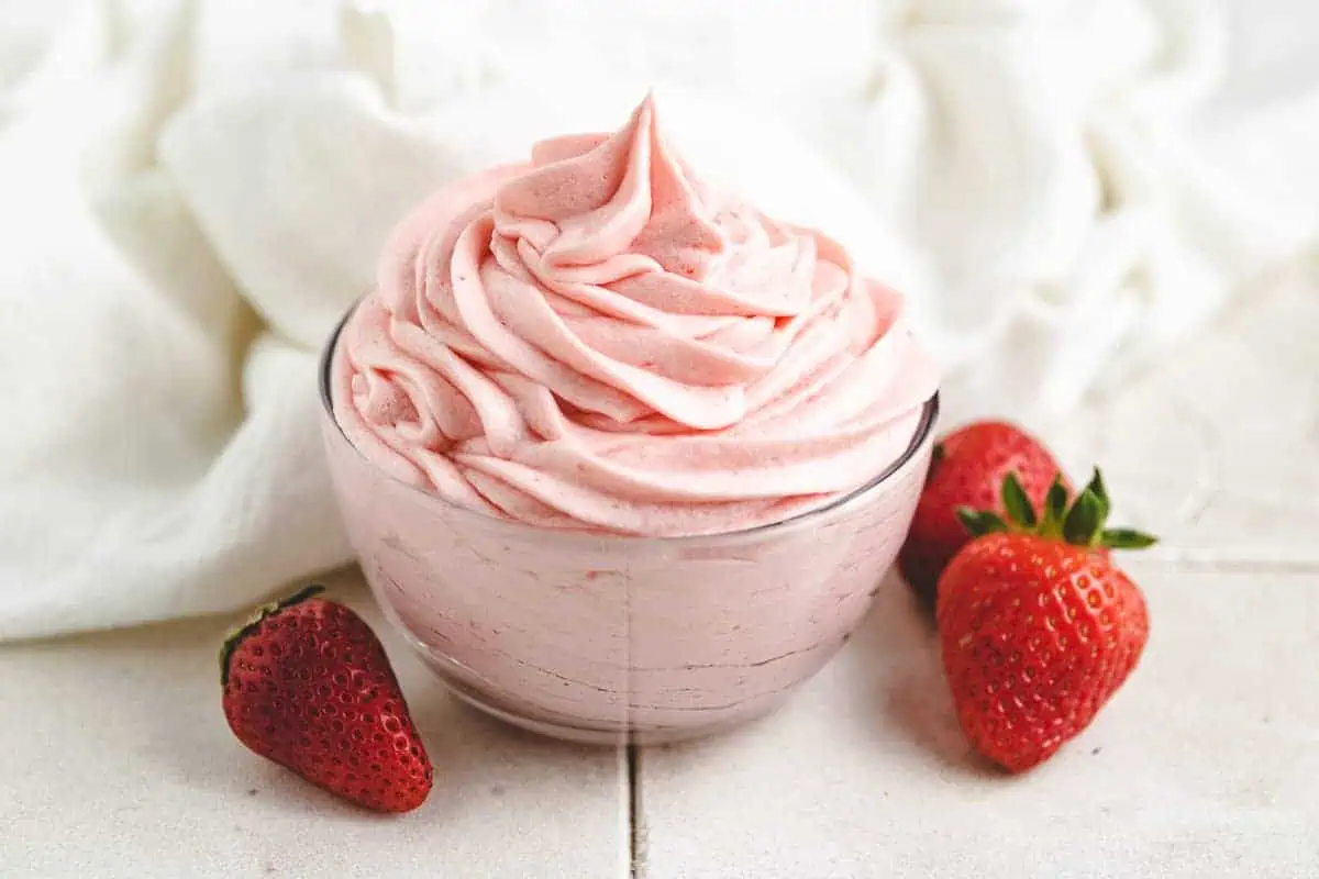 Strawberry frosting next to fresh strawberries.