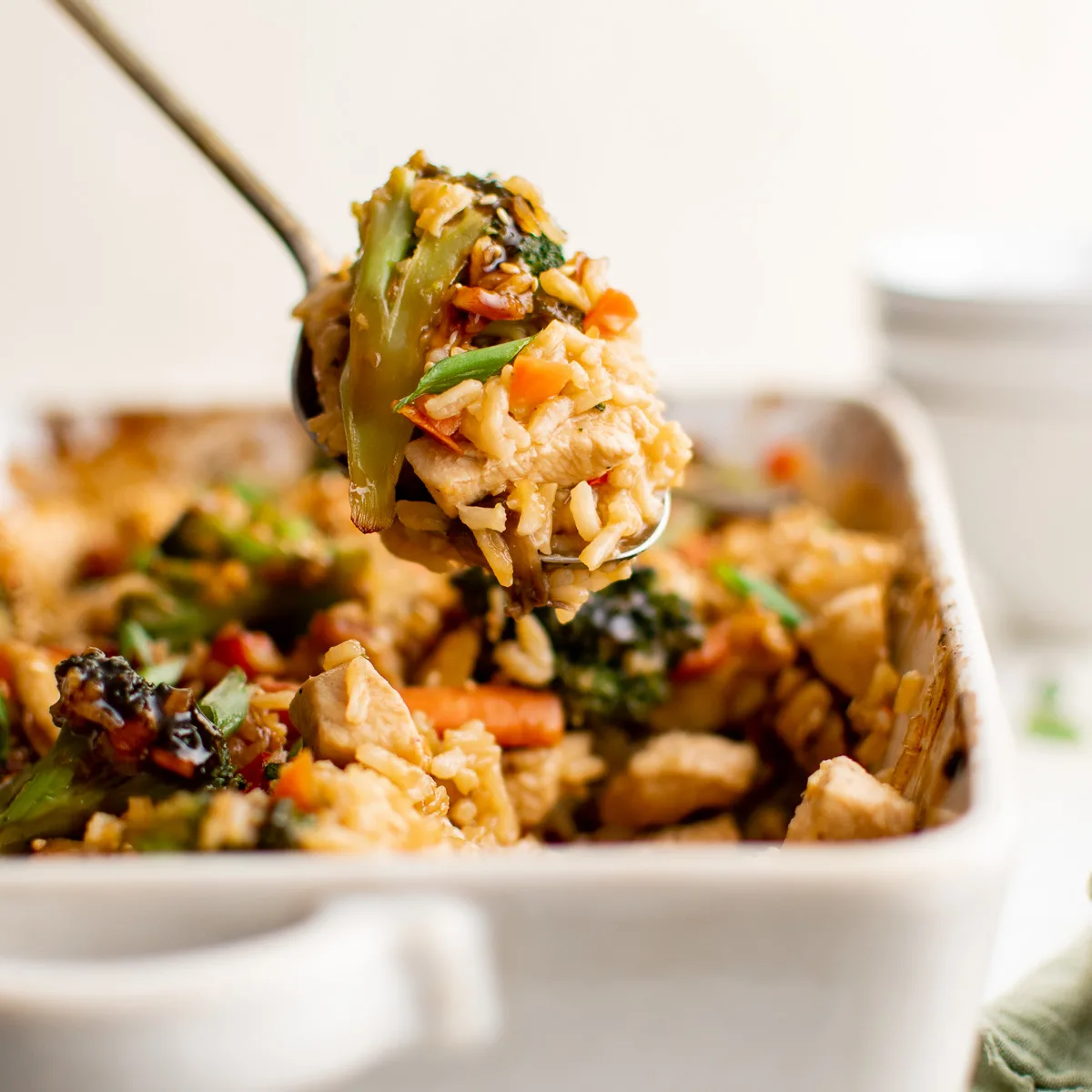 Serving of teriyaki chicken casserole being removed from a dish.