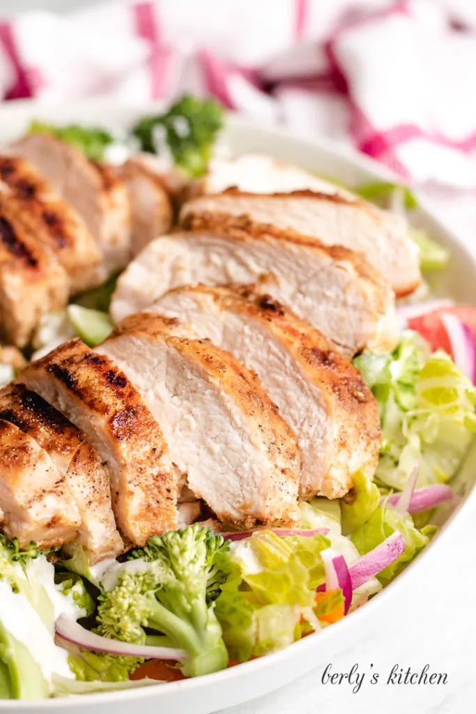 Grilled and sliced chicken served over a salad.