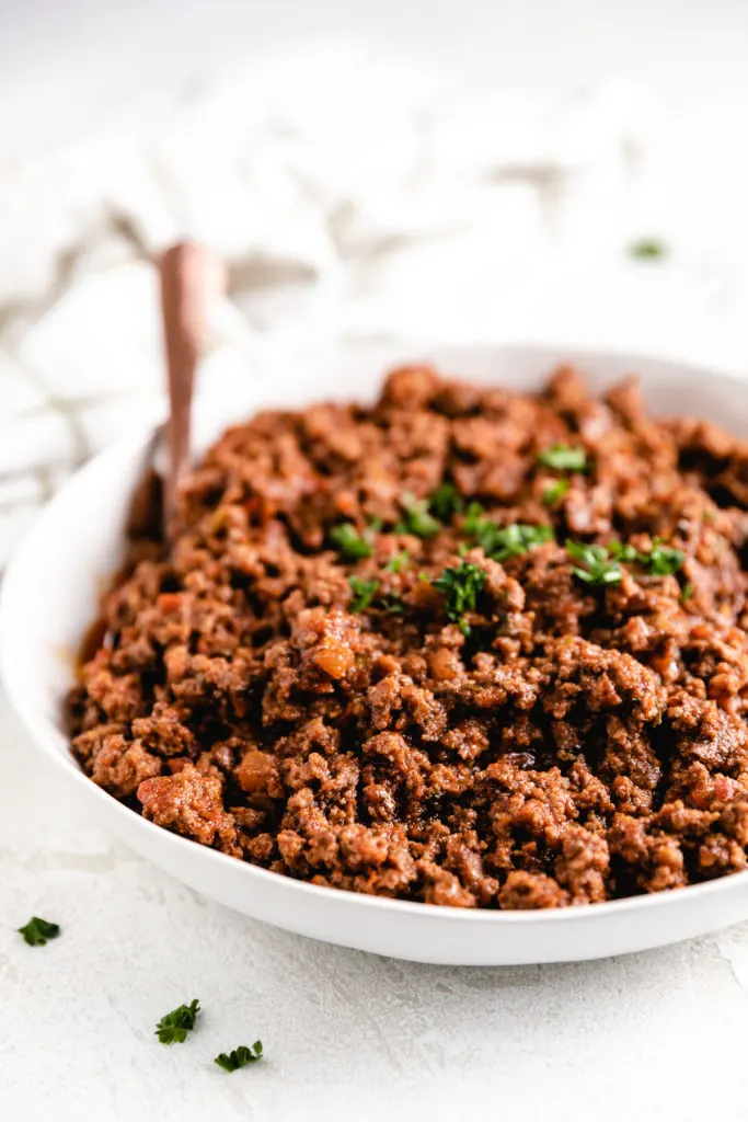 Side view of seasoned ground beef in a large bowl.