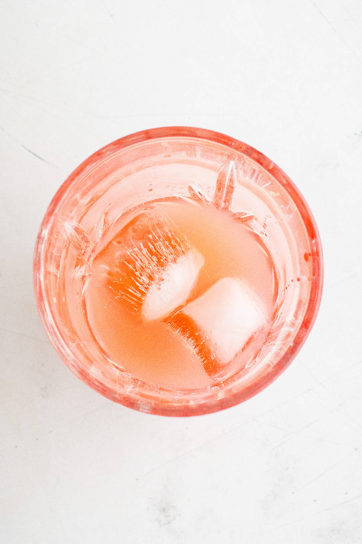 Top down view of ice, pineapple juice and grenadine in a cup.