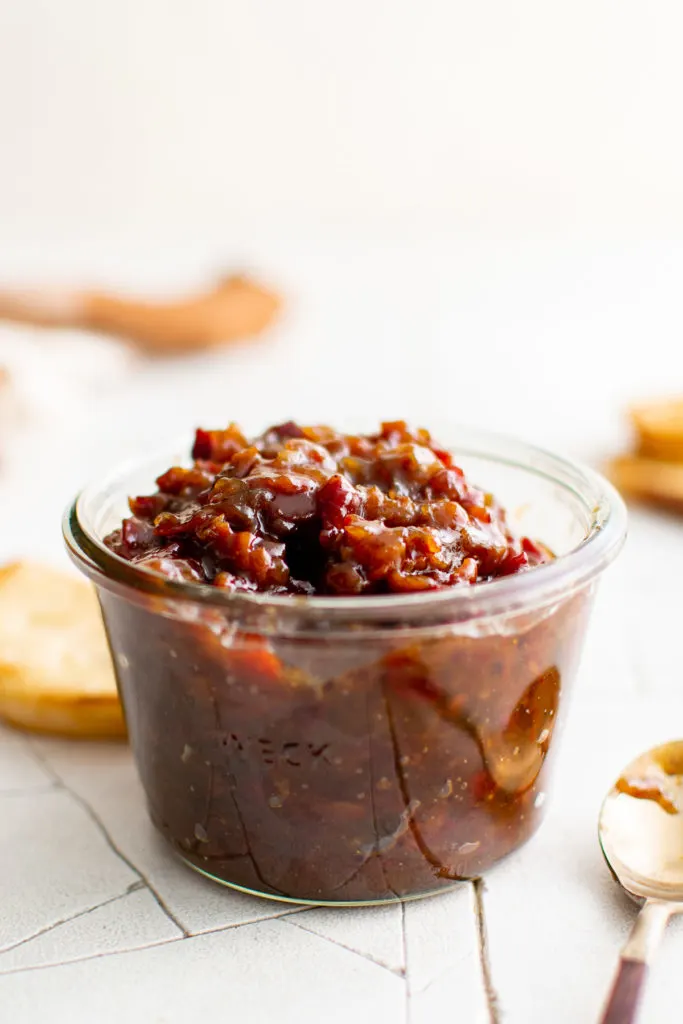 Side view of bacon jam in a glass jar.