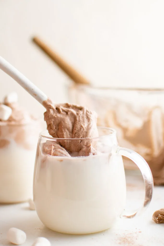 Spoon placing silky hot cocoa into warm milk.