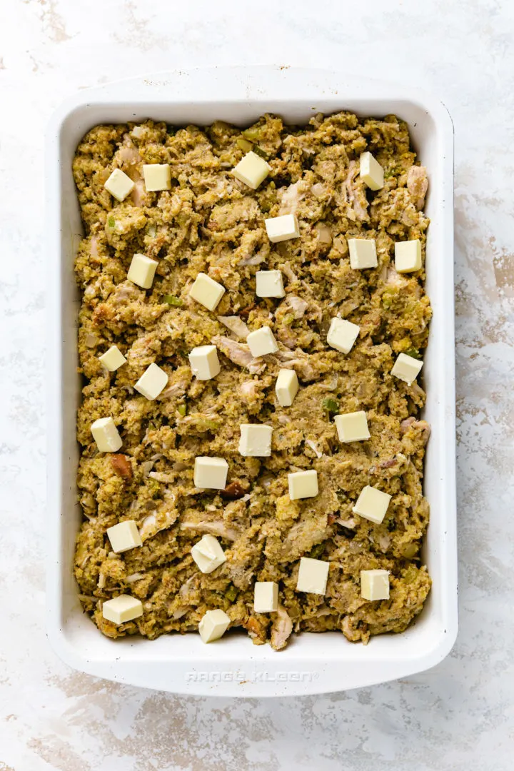 Butter dotted on top of unbaked dressing in a pan.