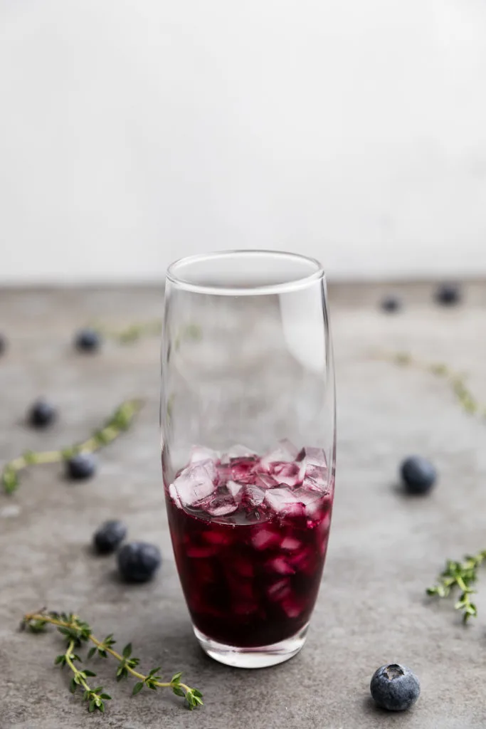 Blueberry thyme syrup poured into a glass.