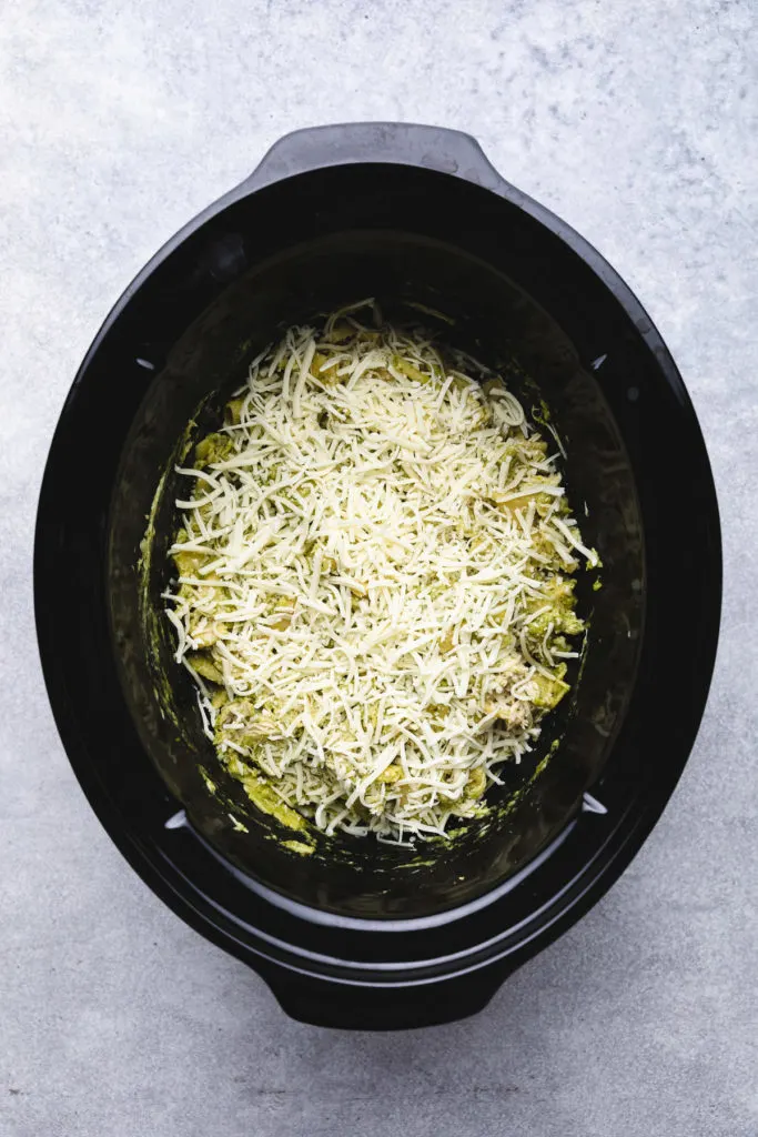 Shredded cheese on top of pasta in a crockpot.