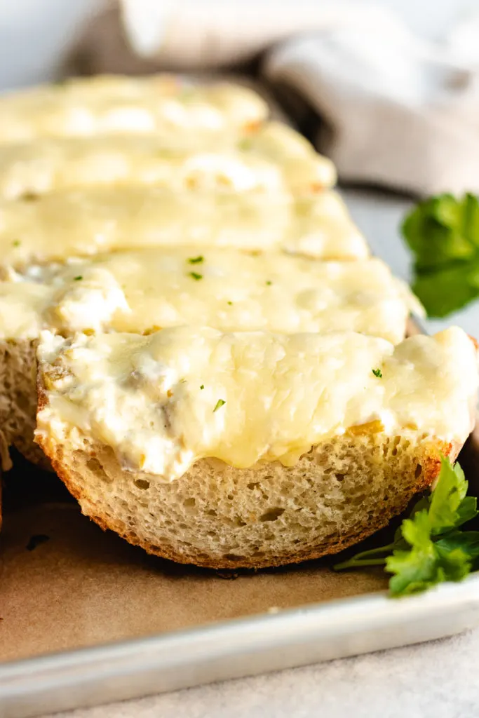 Side view of a loaf of sliced cheesy bread.