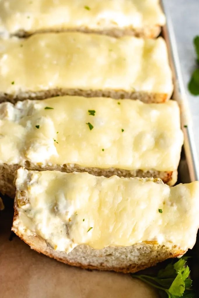 Close up view of melted cheese on a loaf of green chile cheese bread.