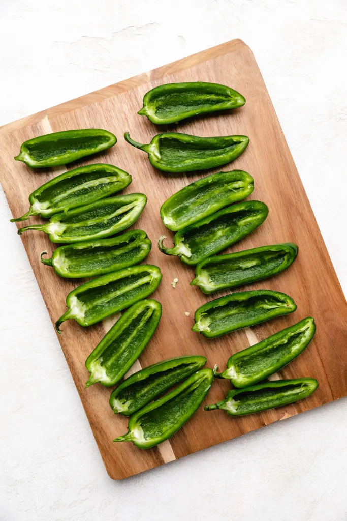 Deseeded jalapeños on a cutting board.