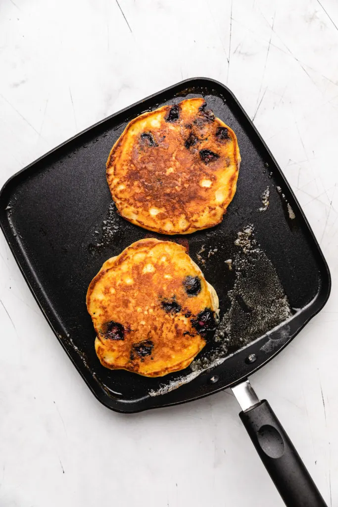 Golden brown pancakes on a griddle.